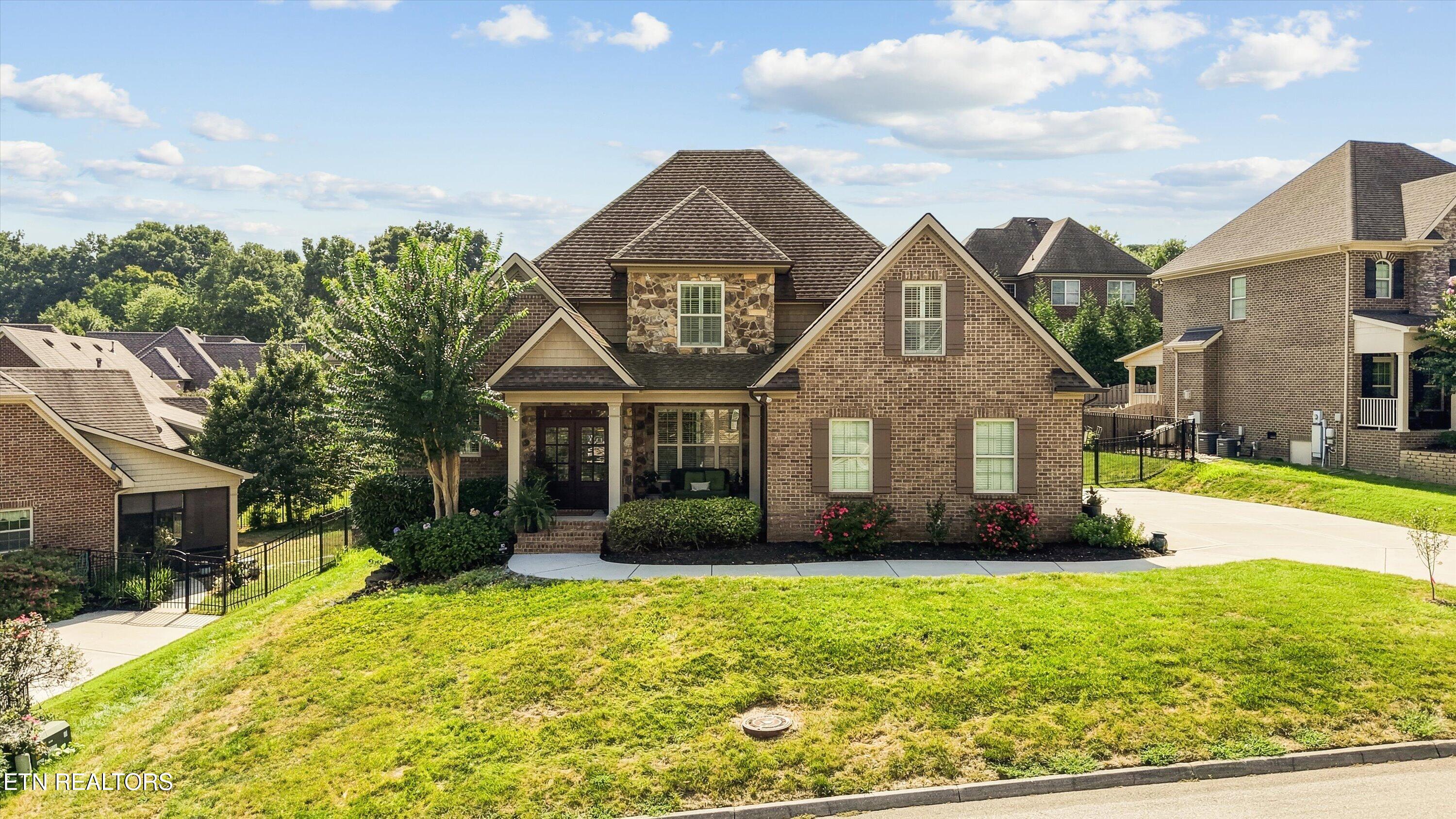 Two-story brick and stone home with multiple gables, a covered porch, and a broad lawn.