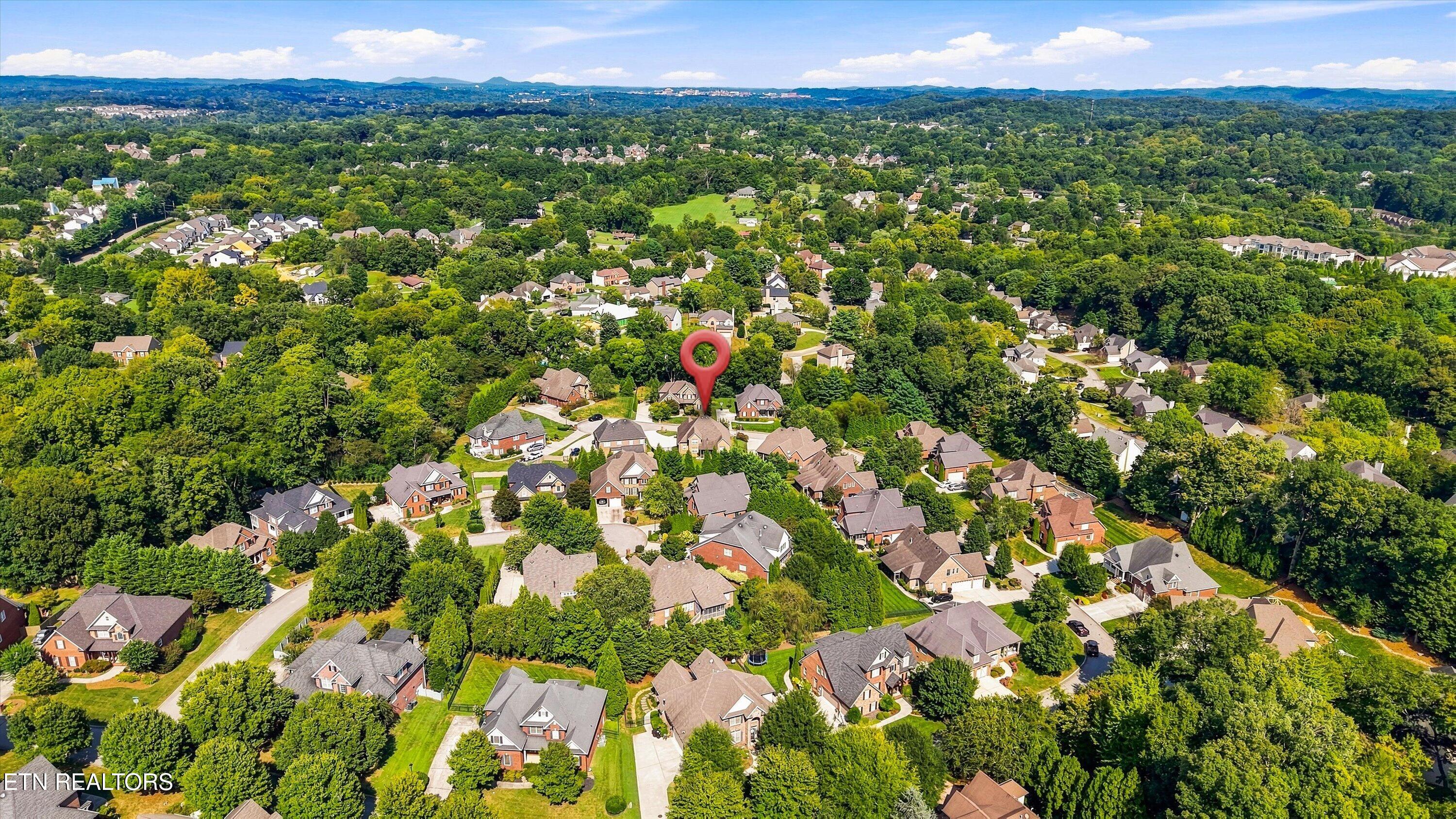 Aerial view of a home marked by a red pin in a leafy Knoxville neighborhood.