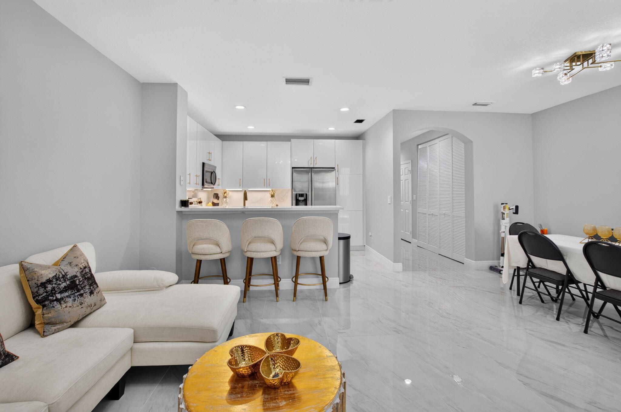 Open-plan living room with white sectional, breakfast bar, and dining area.