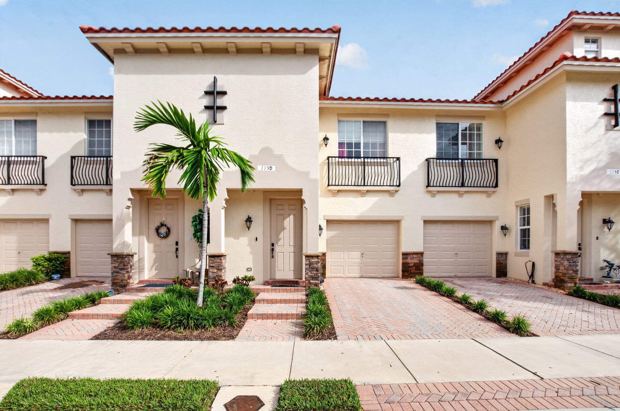 Attached residence with red tile roofs, black balconies, and a palm tree beside the entrance.