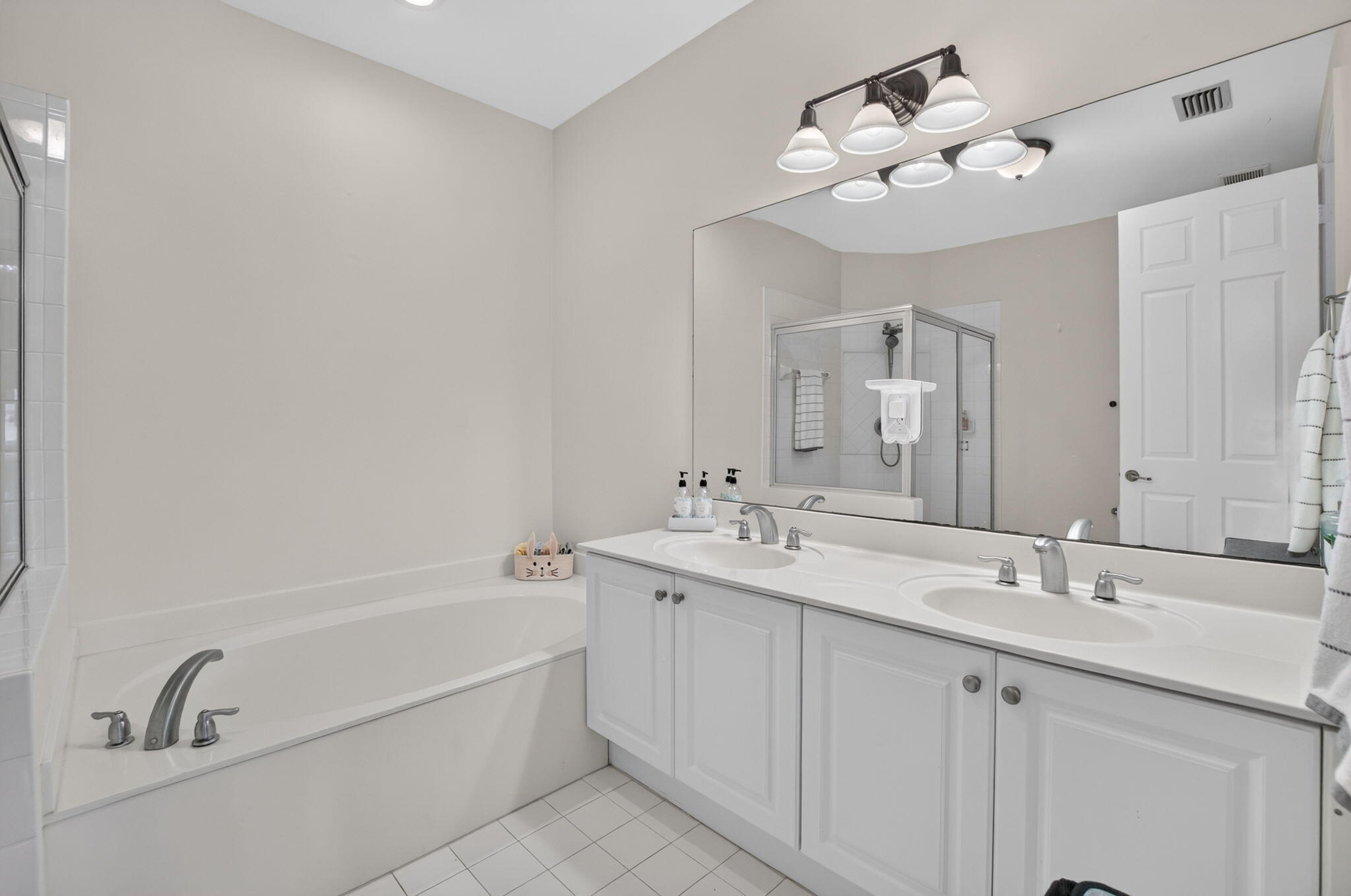 Bathroom with a double-sink vanity, built-in soaking tub, and glass-enclosed shower.