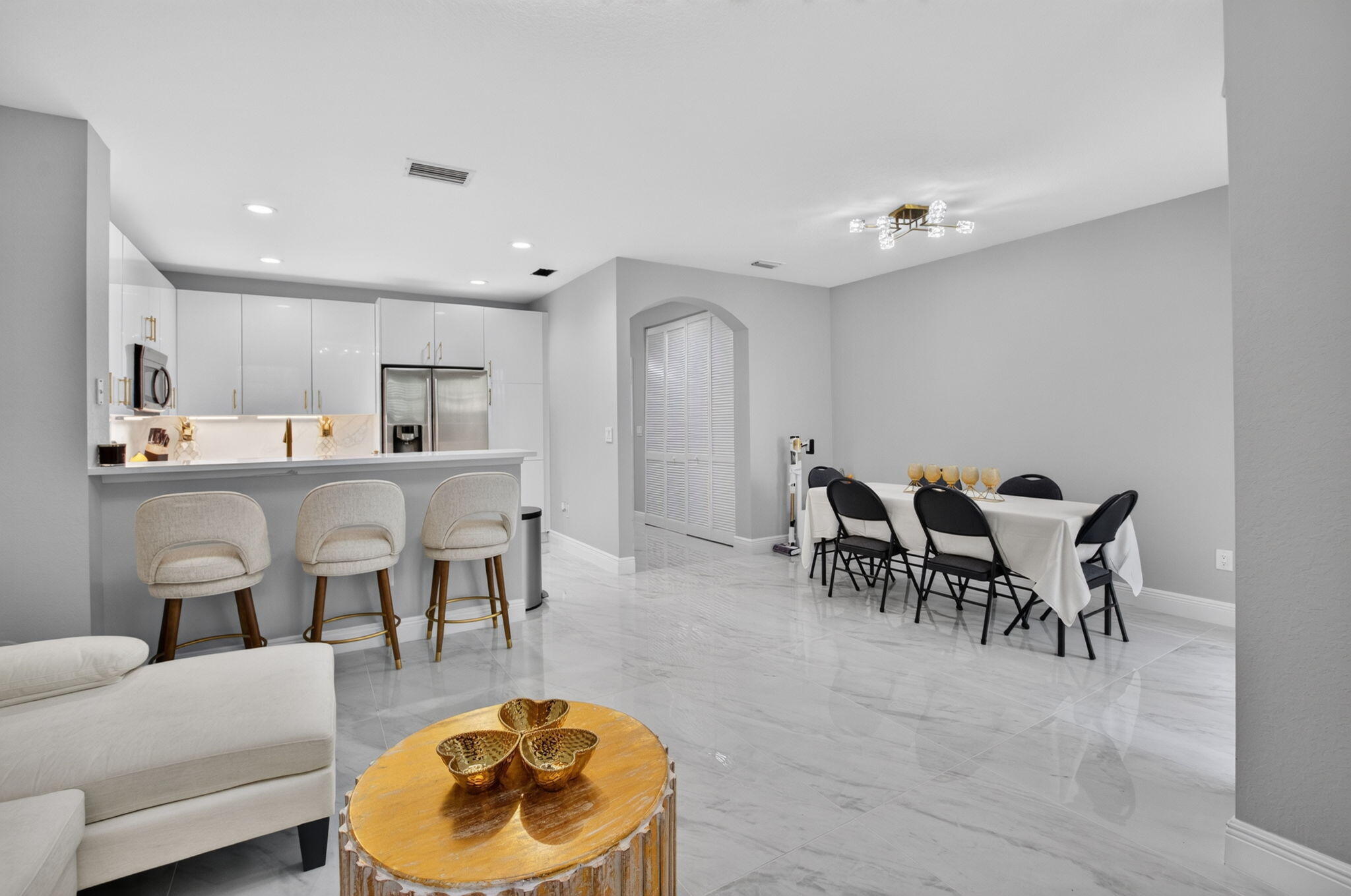 Open-plan kitchen and dining area with white cabinetry, a breakfast bar, and a table with black chairs.