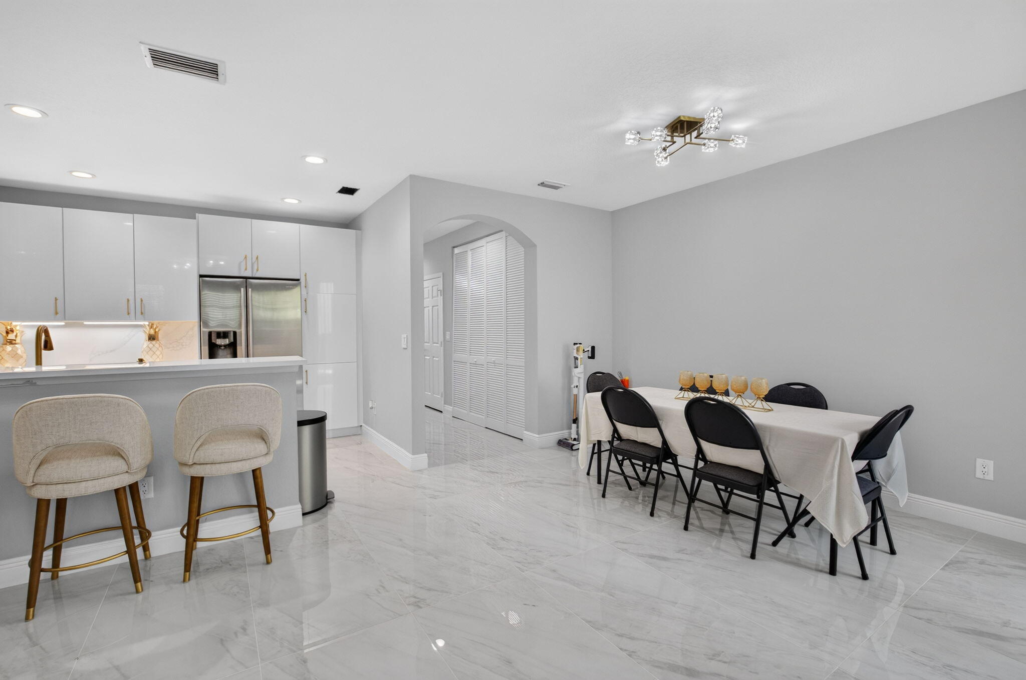 Kitchen and dining area with a white breakfast bar, stainless steel appliances, and a set dining table.