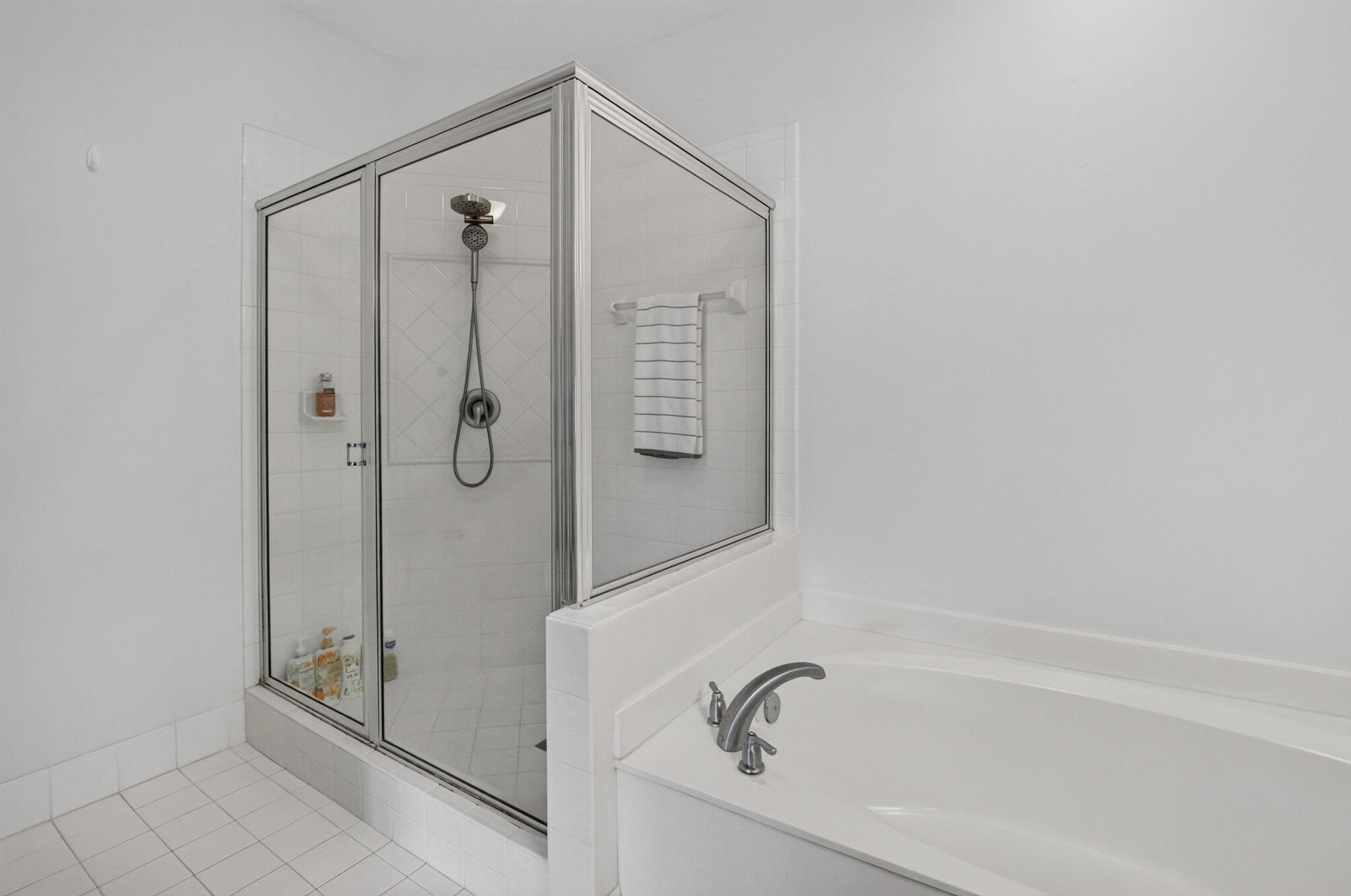 Bathroom with a glass-enclosed shower and white bathtub.