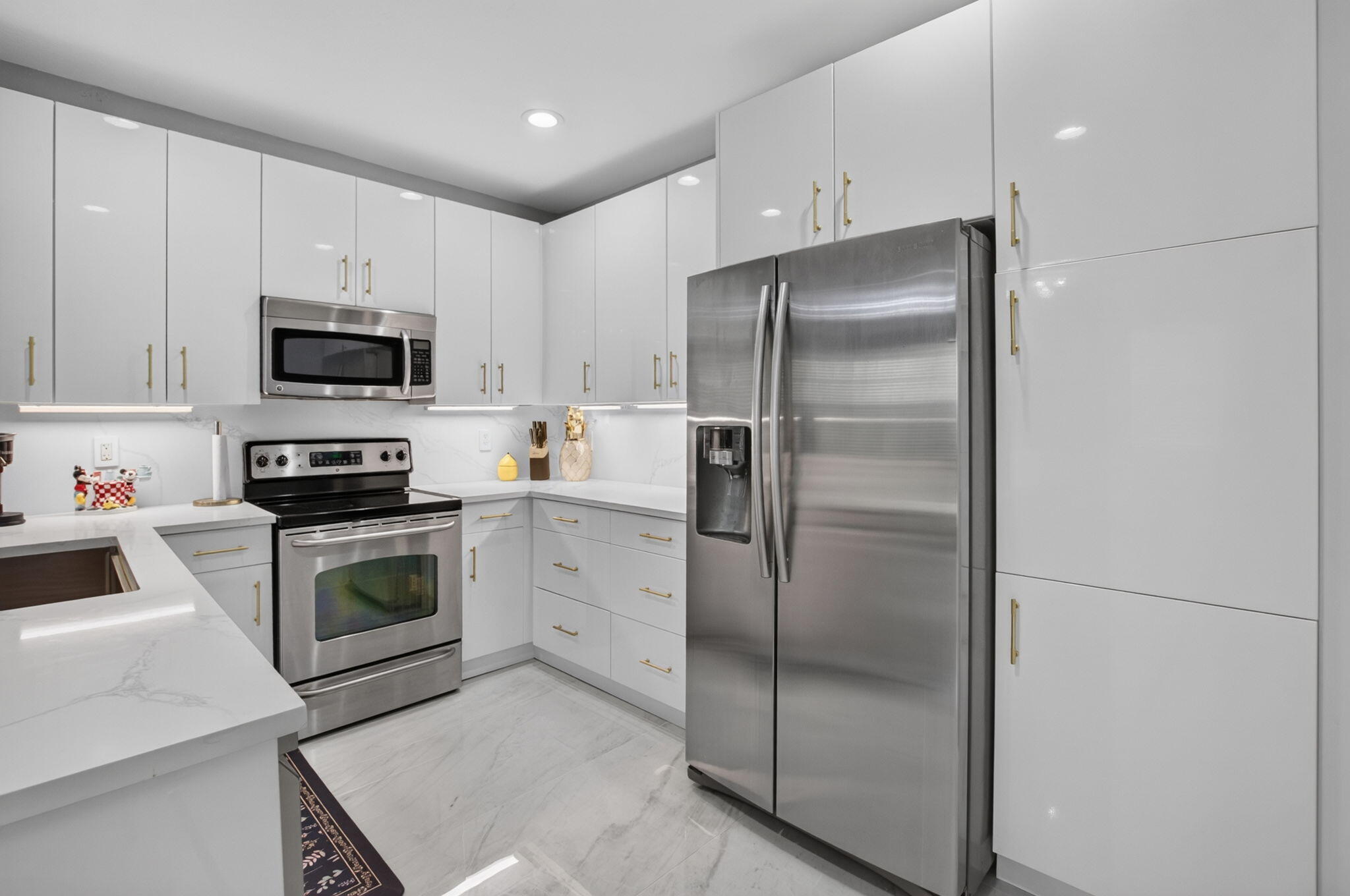 Modern kitchen with white cabinetry, marble-look counters, and stainless steel appliances.