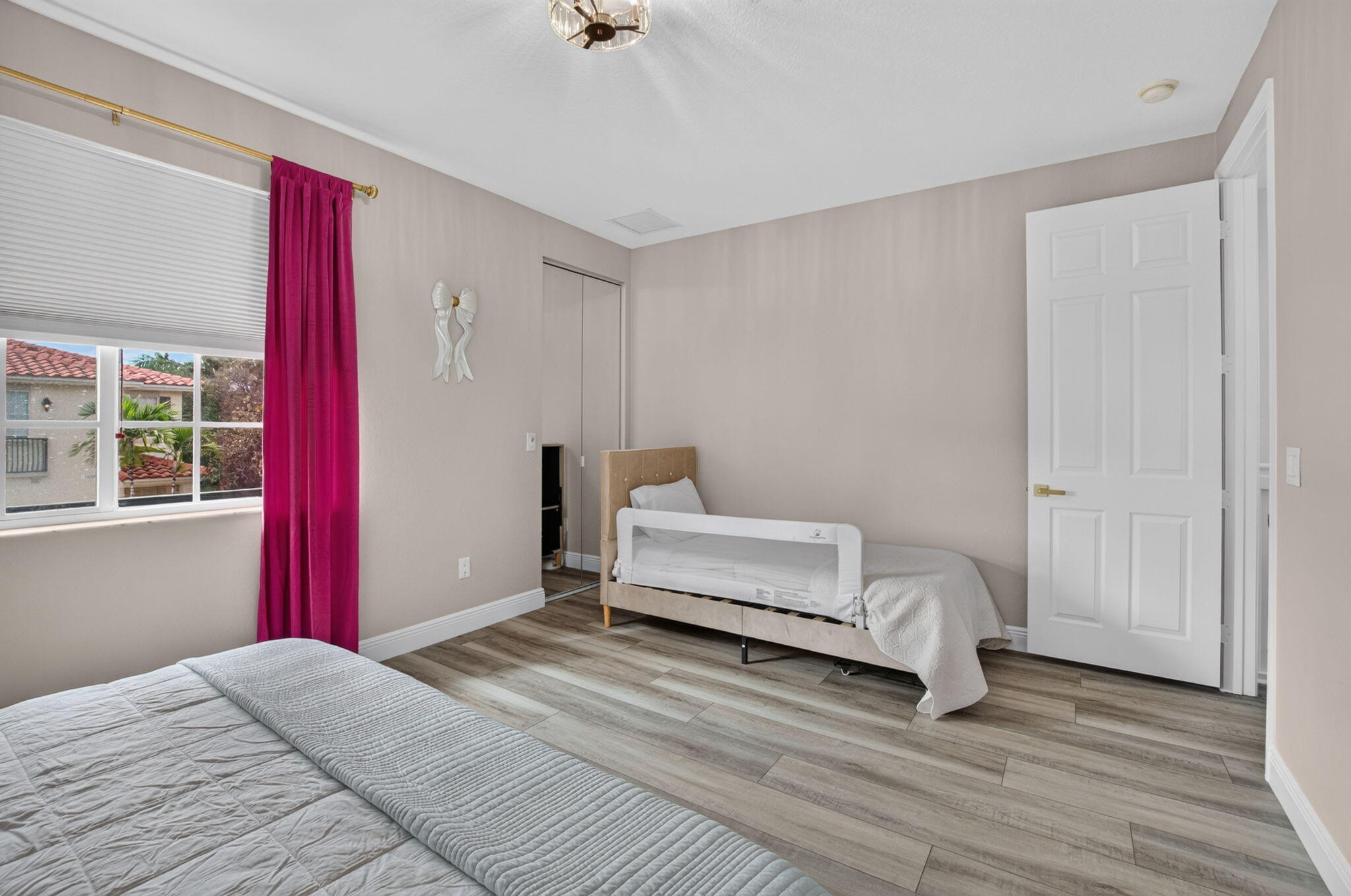 Bedroom with two beds, a white safety rail, and a bright magenta curtain.