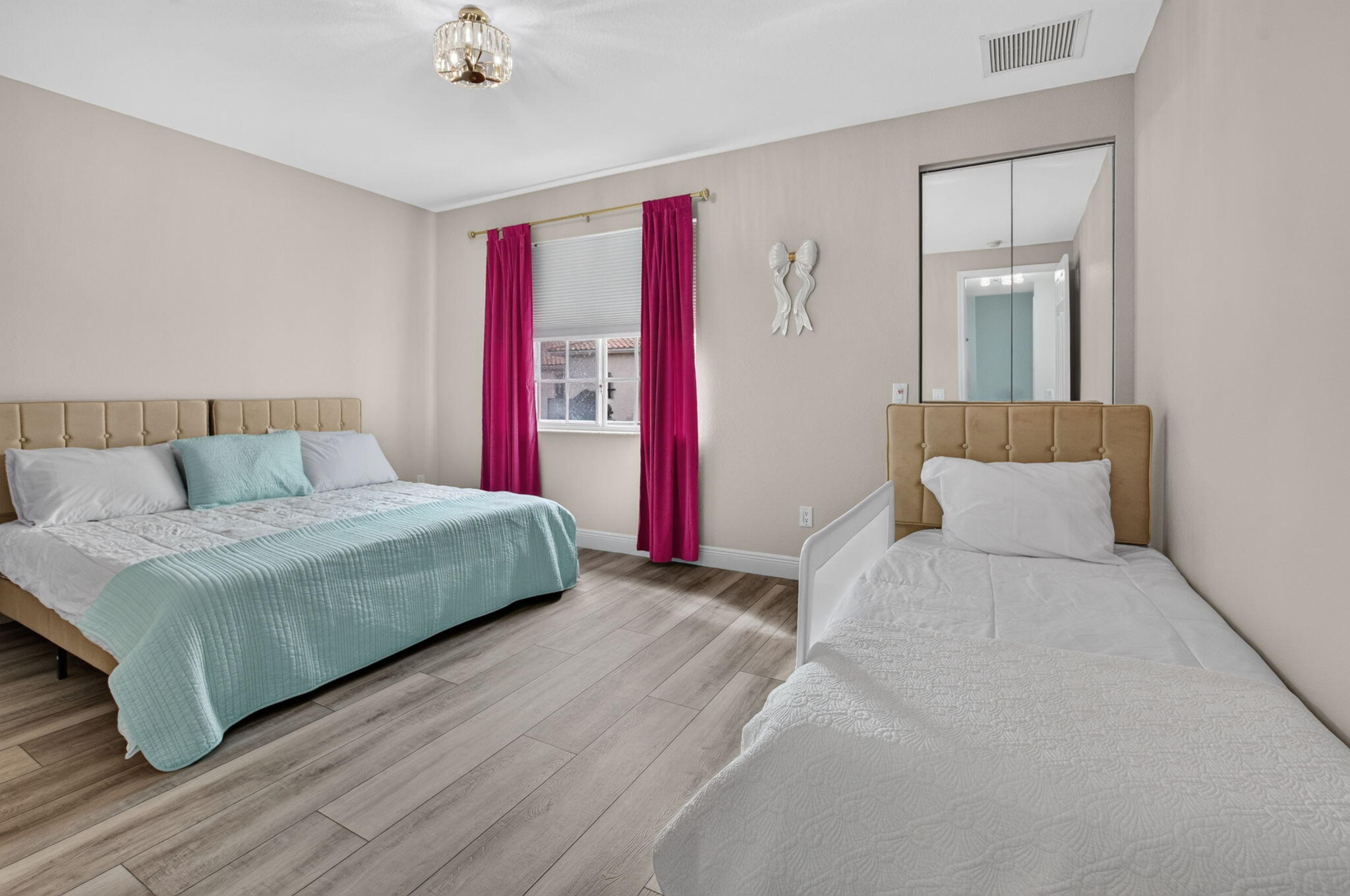 Bedroom with a queen bed, single bed, mirrored closet doors, and magenta curtains.