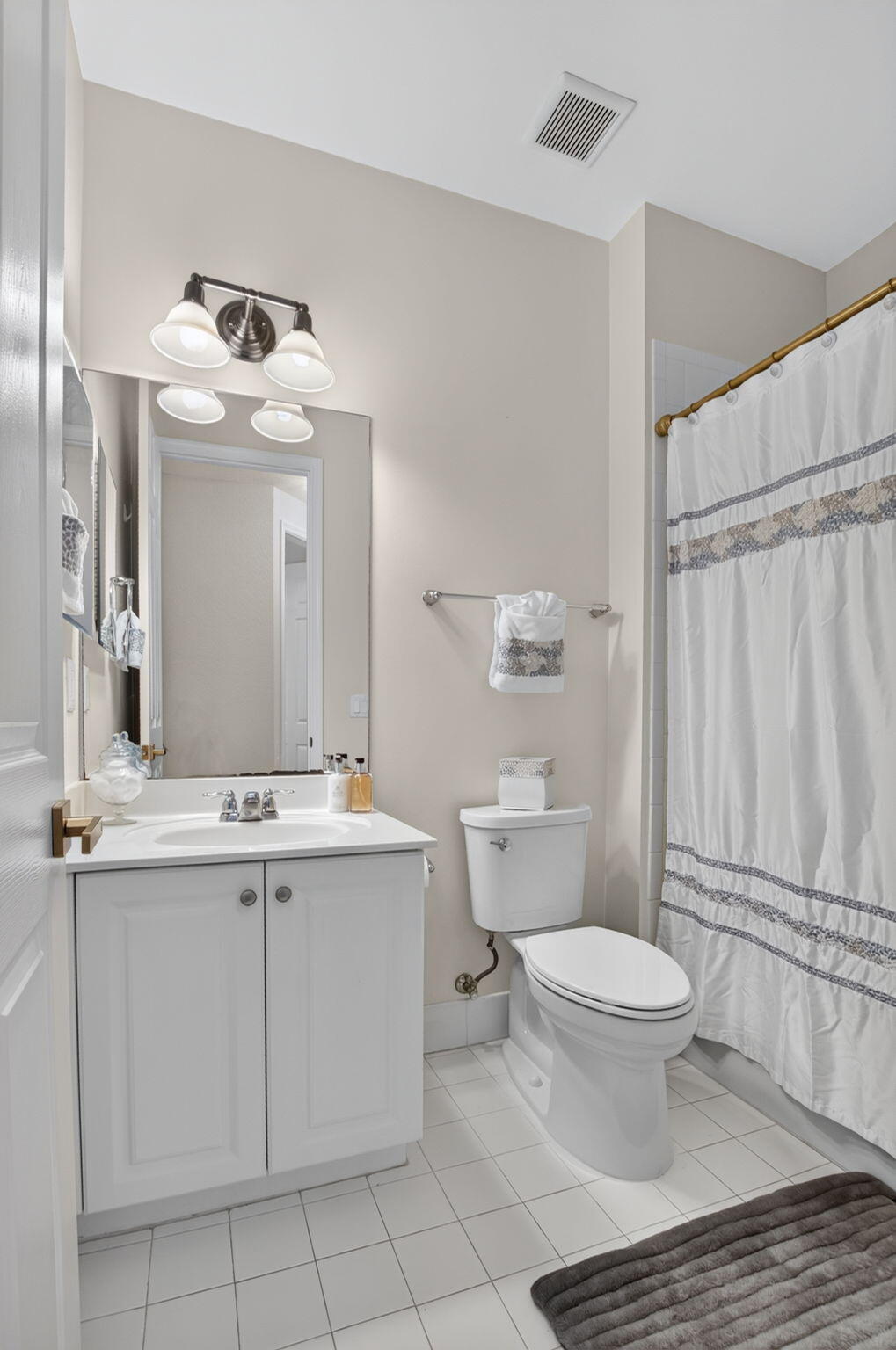 Bathroom with a white vanity, toilet, and patterned shower curtain.