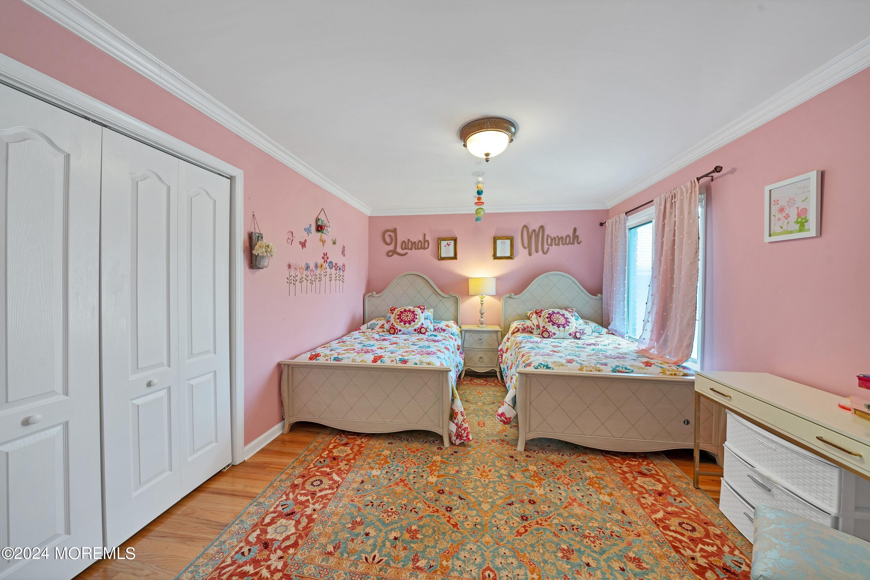 Pink bedroom with matching twin beds, floral bedding, and a large patterned rug.