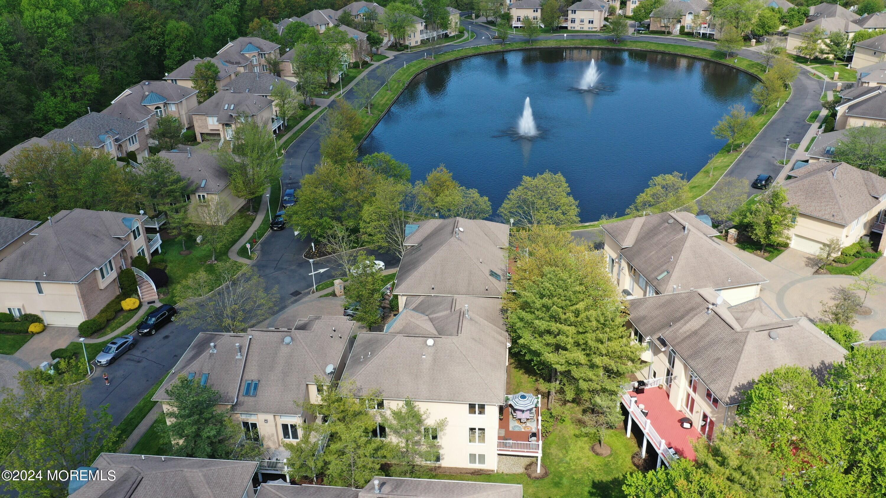 Aerial view of a residential community around a pond with two fountains.