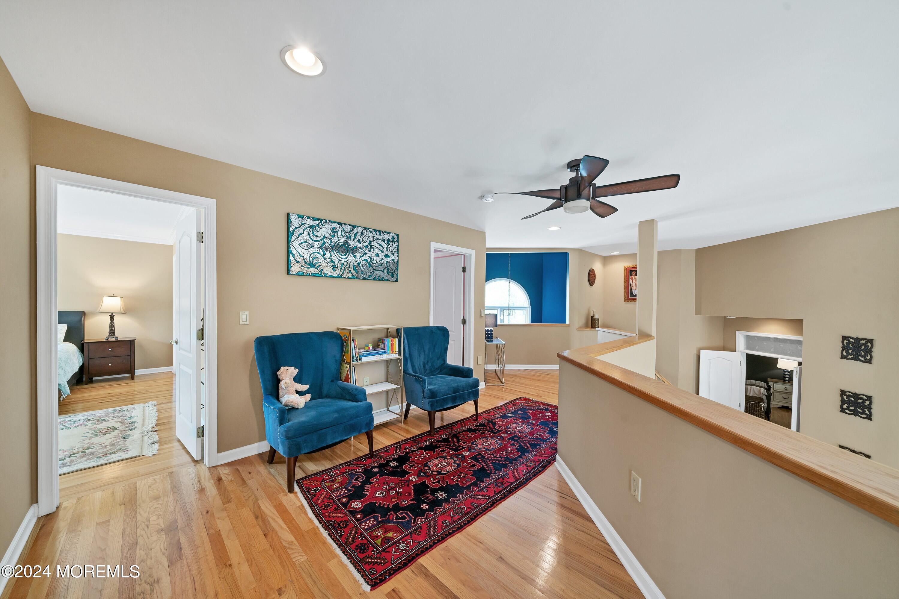 Upstairs sitting area with teal armchairs, hardwood floors, and a red patterned rug.
