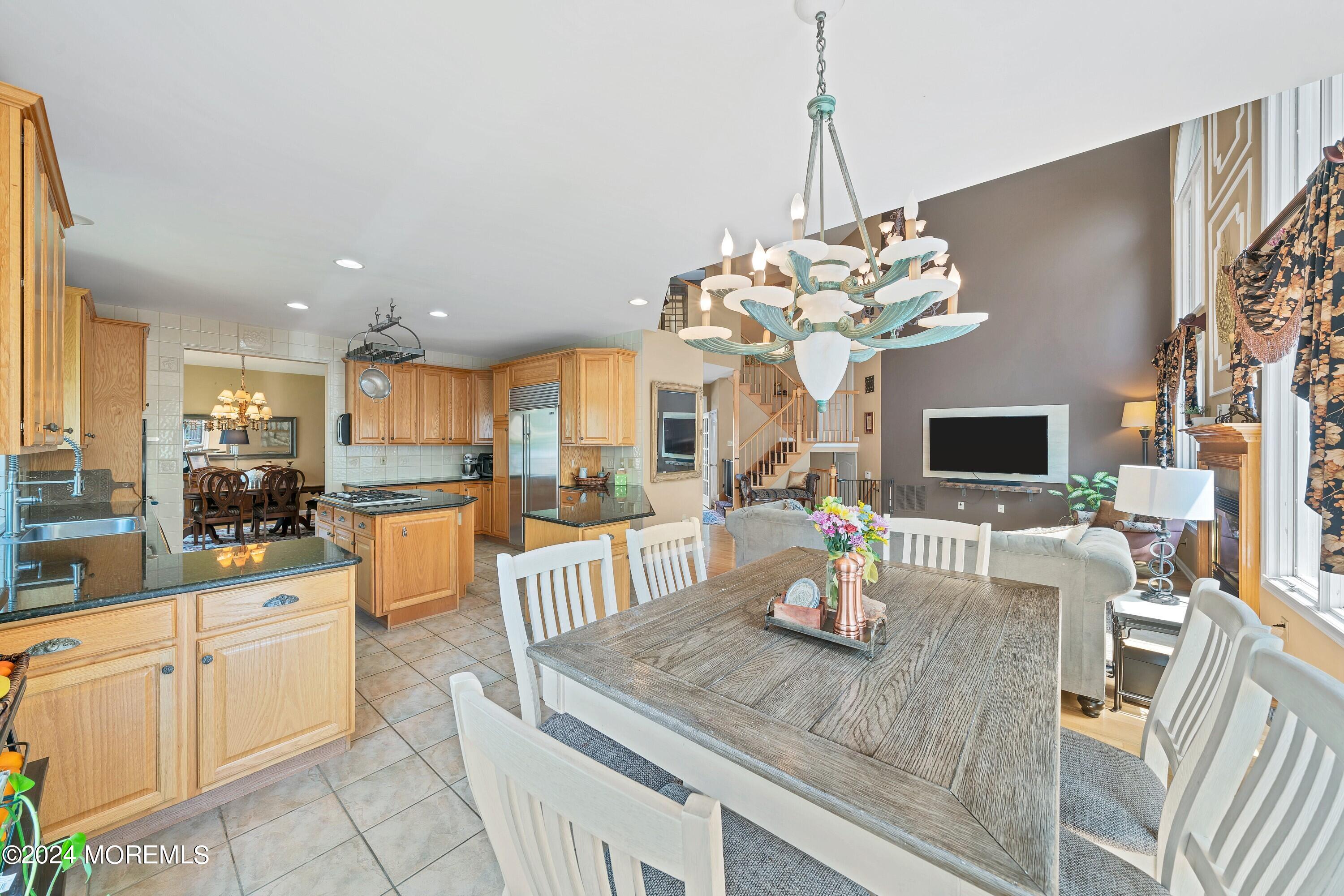 Open-plan kitchen and dining room with wood cabinets, a large table, and adjoining living area.