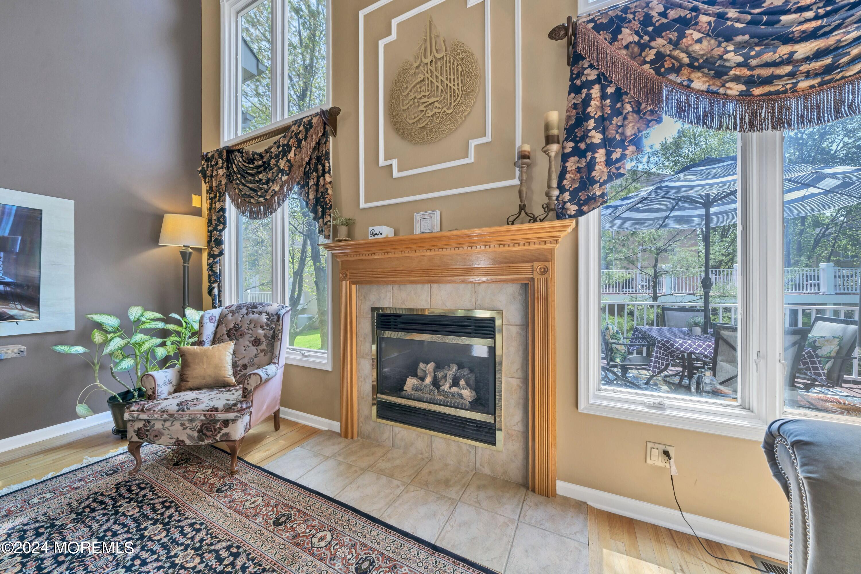 Living room with a gas fireplace, tall windows, and sliding doors opening onto a furnished deck.