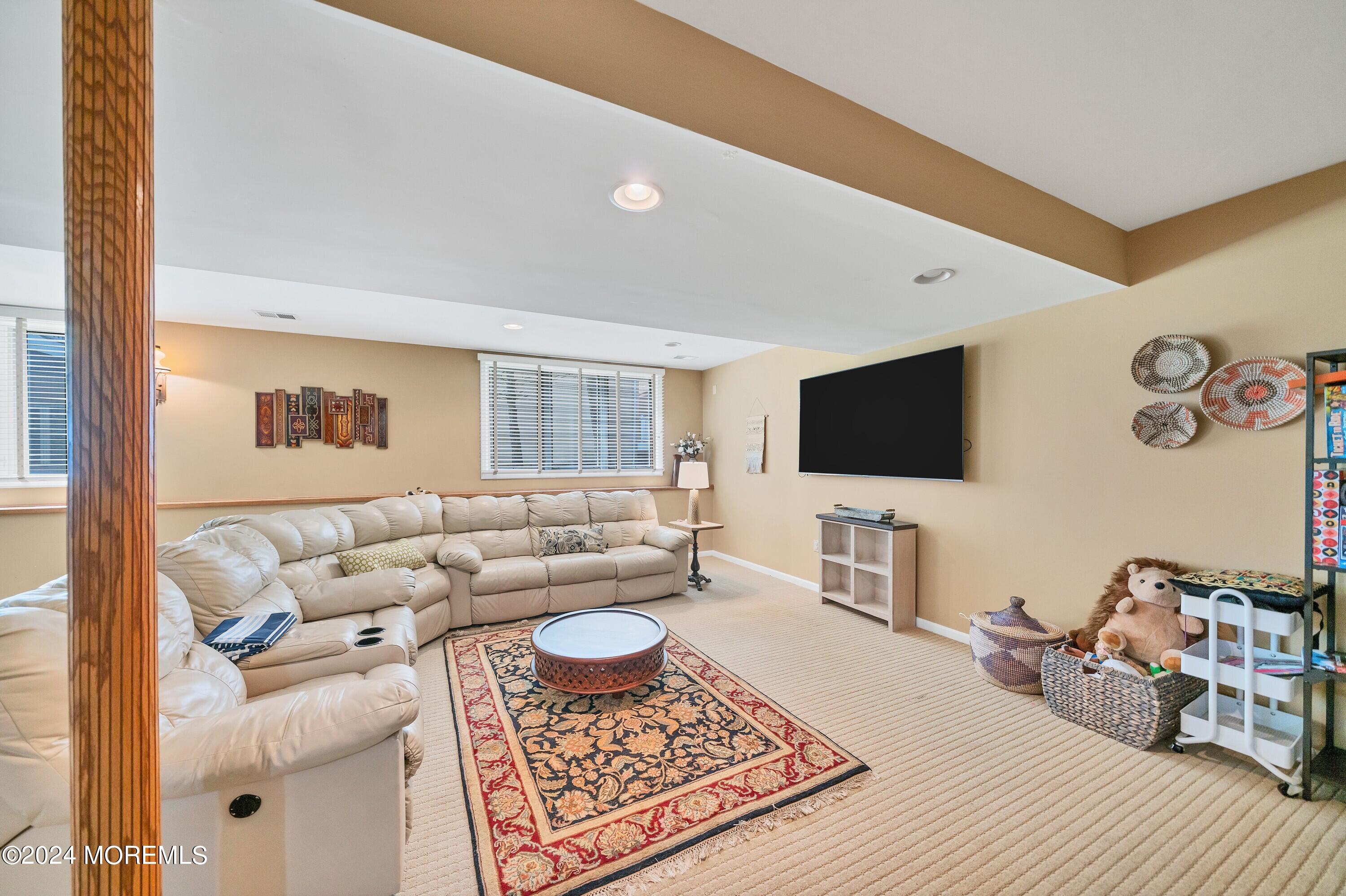 Furnished living room with a cream sectional, patterned rug, round coffee table, and wall-mounted television.