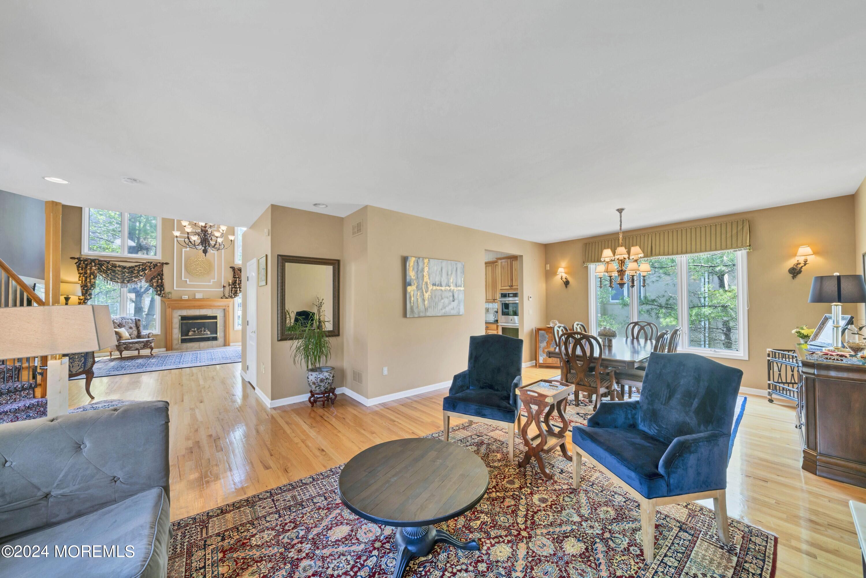 Open-plan living and dining room with a fireplace, blue armchairs, hardwood floors, and large windows.