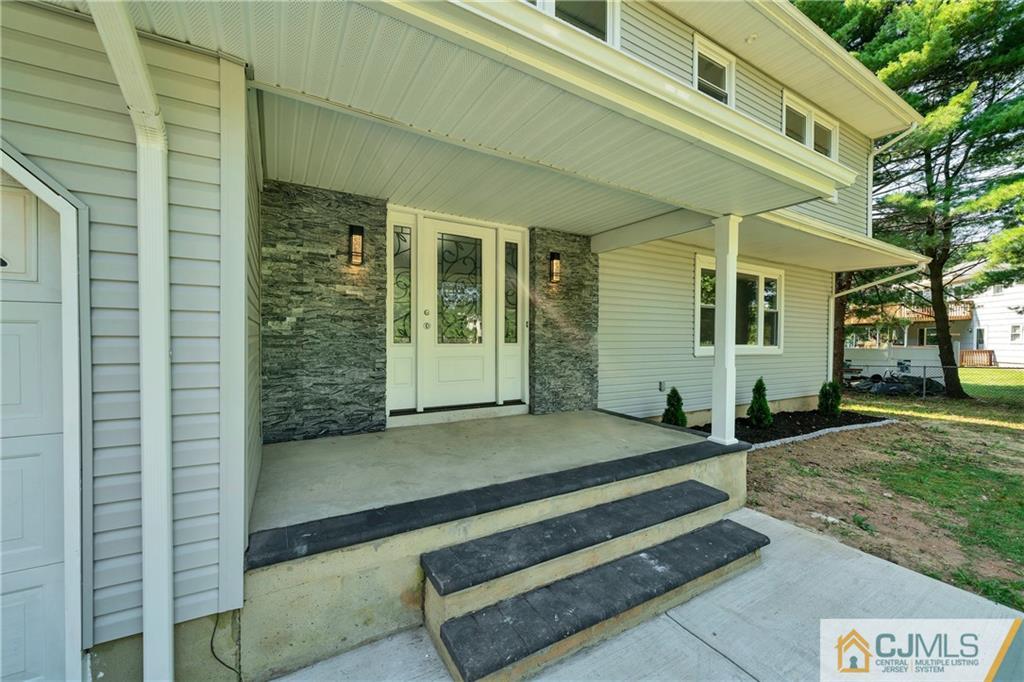 Covered front entrance with decorative glass double doors, a stone accent wall, and concrete steps.