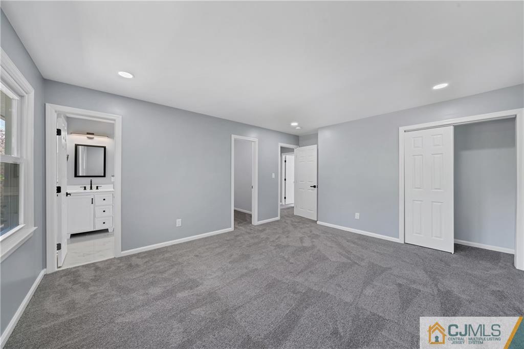 Vacant carpeted bedroom with an open closet and doorway to an ensuite bathroom.