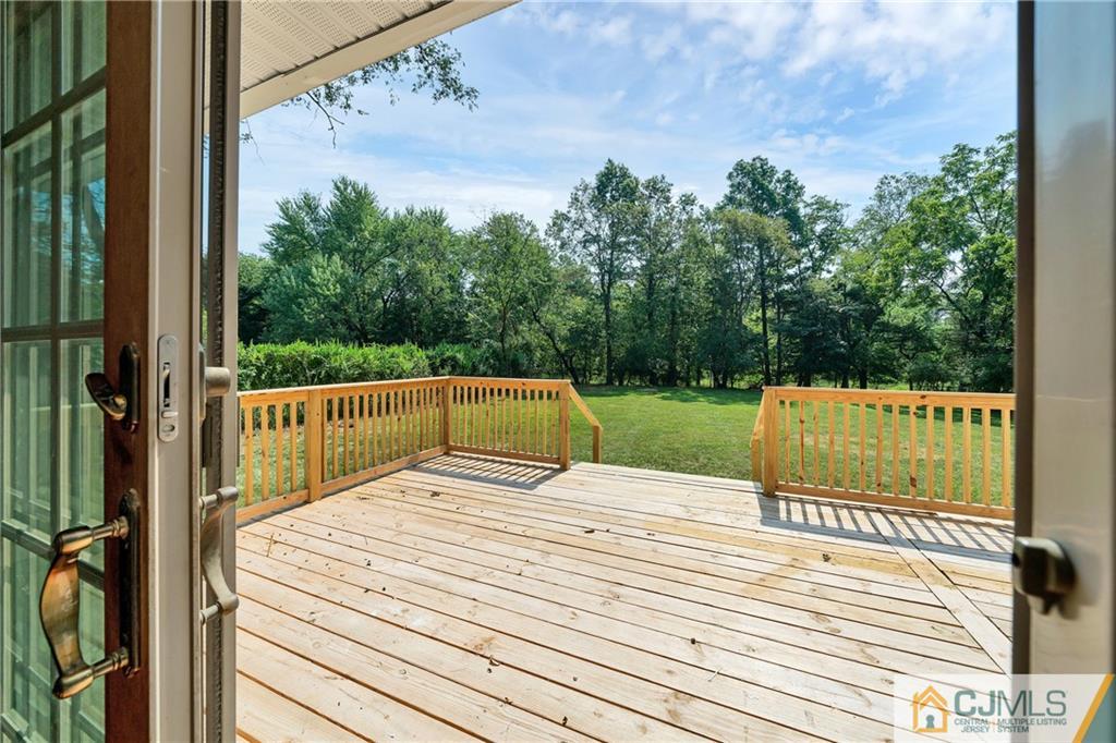 Wooden deck overlooking a grassy yard and mature trees.