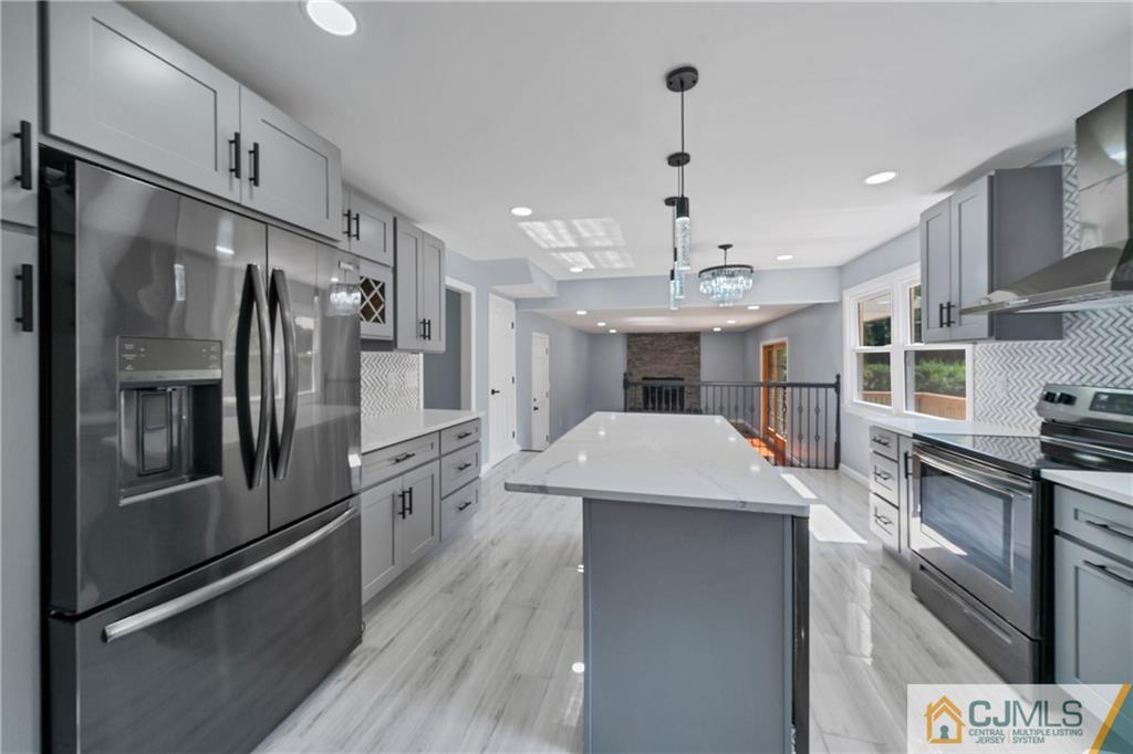 Renovated kitchen with a large white island, gray cabinets, and stainless steel appliances.