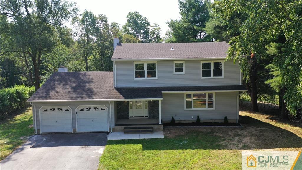 Two-story gray house with an attached two-car garage and mature trees.