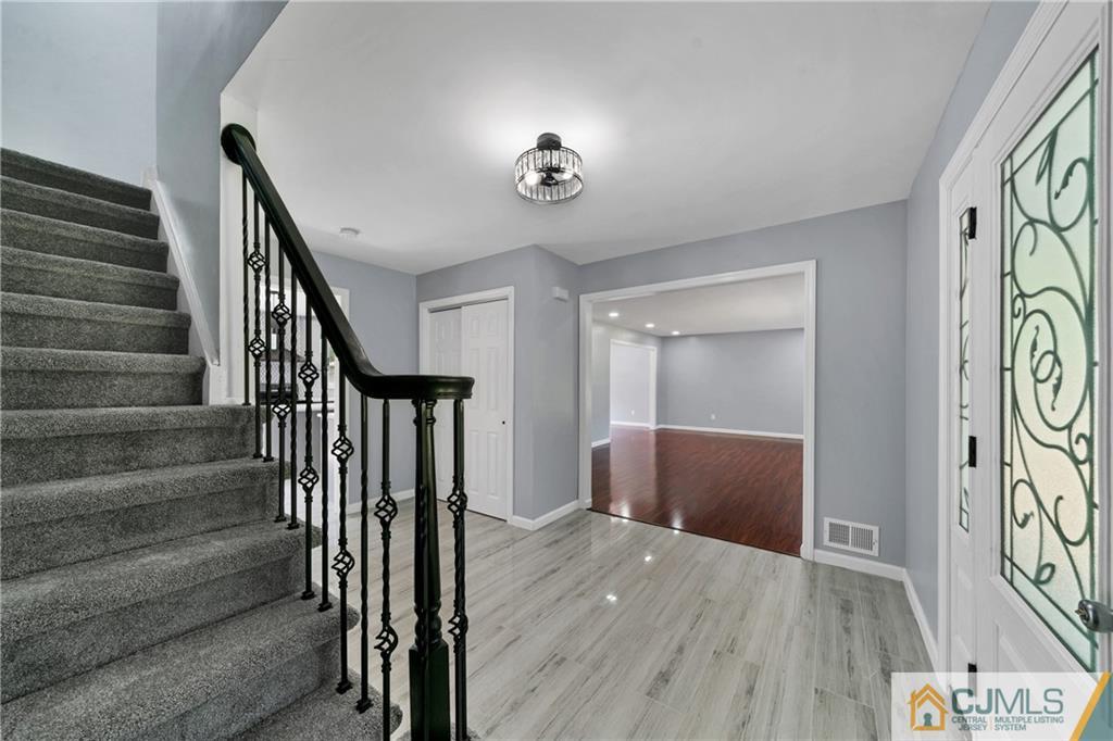 Foyer with a carpeted staircase, black iron railing, and decorative glass front door.