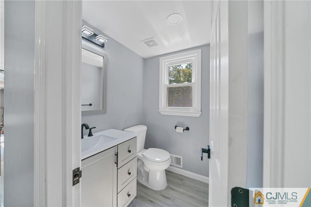 Bathroom with a white vanity, black faucet, toilet, and window.