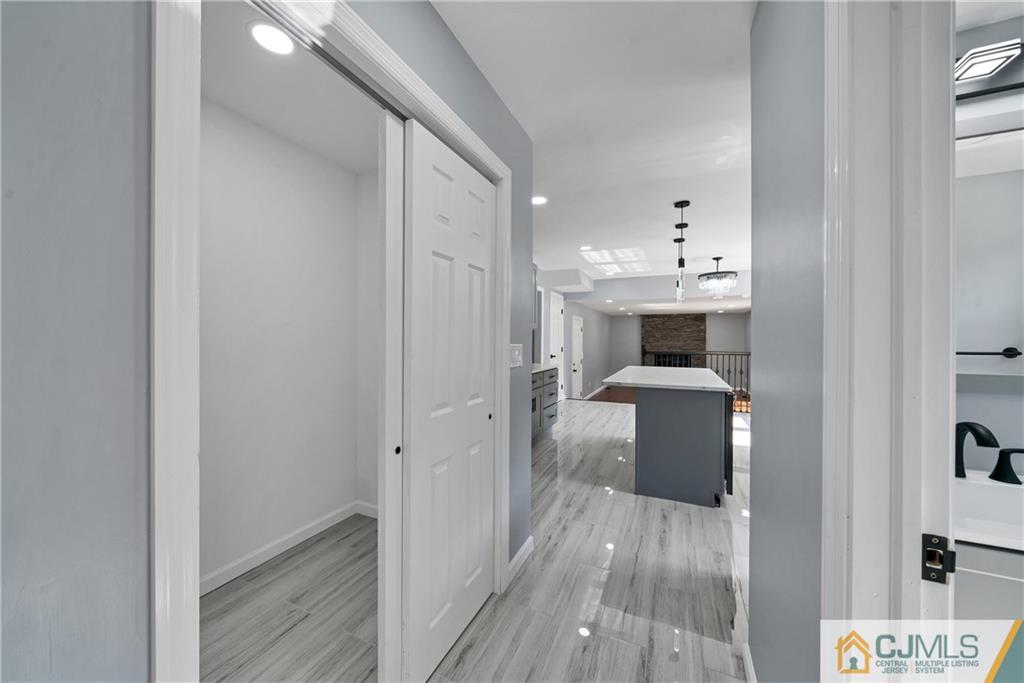 Kitchen with a gray island and white countertop, viewed through a doorway over gray wood-look flooring.