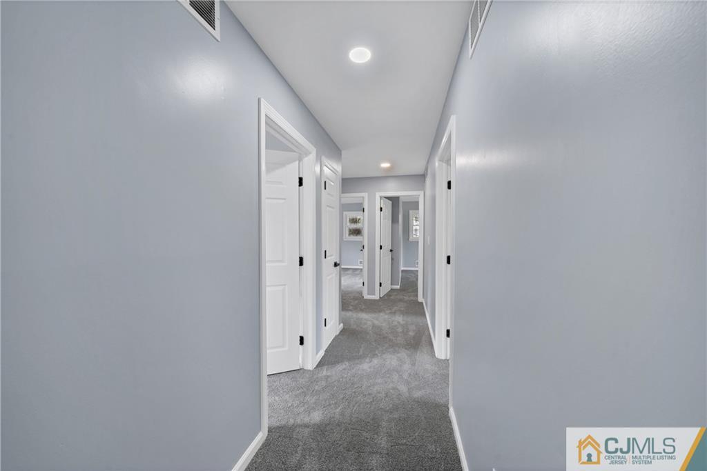 Carpeted hallway with pale blue-gray walls and several open doorways.