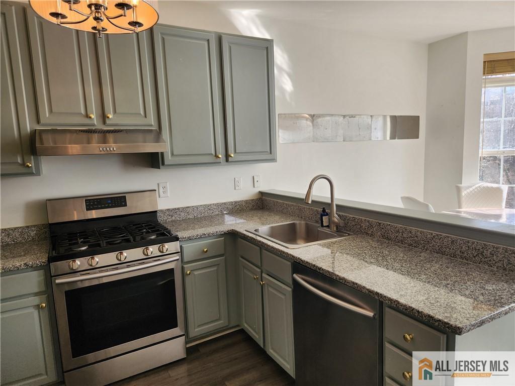 Kitchen with sage cabinets, granite counters, stainless appliances, and a gas range.