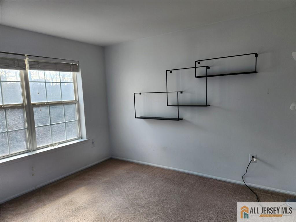 Empty carpeted room with a double window and geometric black wall shelves.