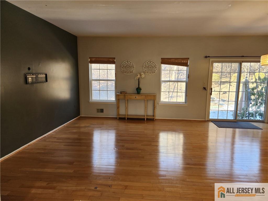 Living room with polished hardwood floors, a dark accent wall, and a glass patio door.