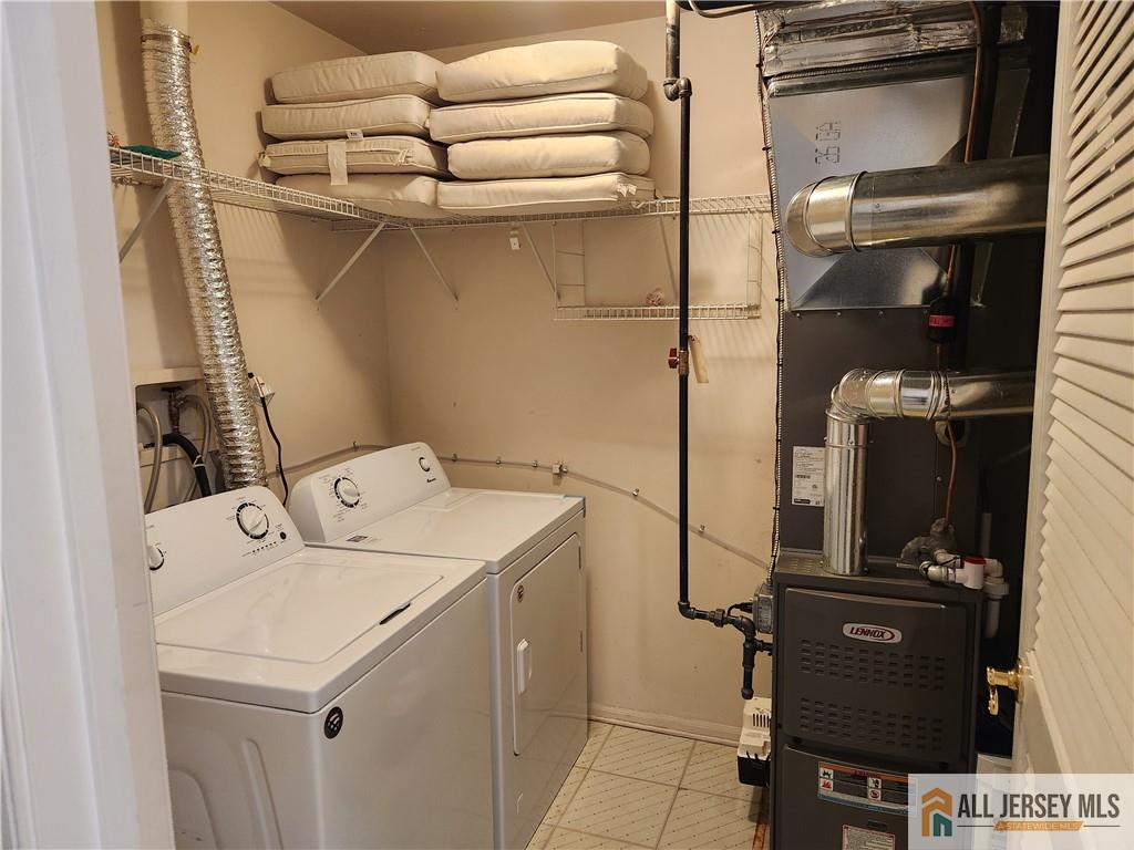 Laundry room with washer and dryer, overhead storage shelves, and exposed furnace ductwork.