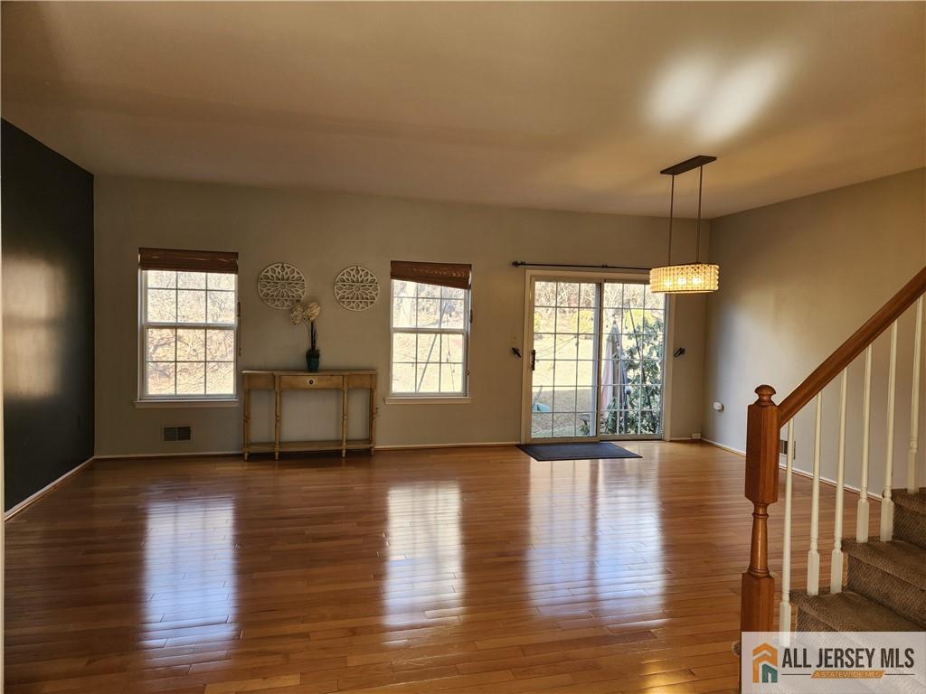 Living room with polished hardwood floors, sliding glass doors, and a staircase.