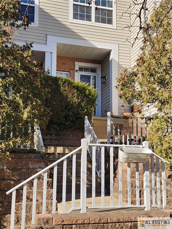 Townhouse entrance with a blue front door, stone retaining walls, and white-railed steps.