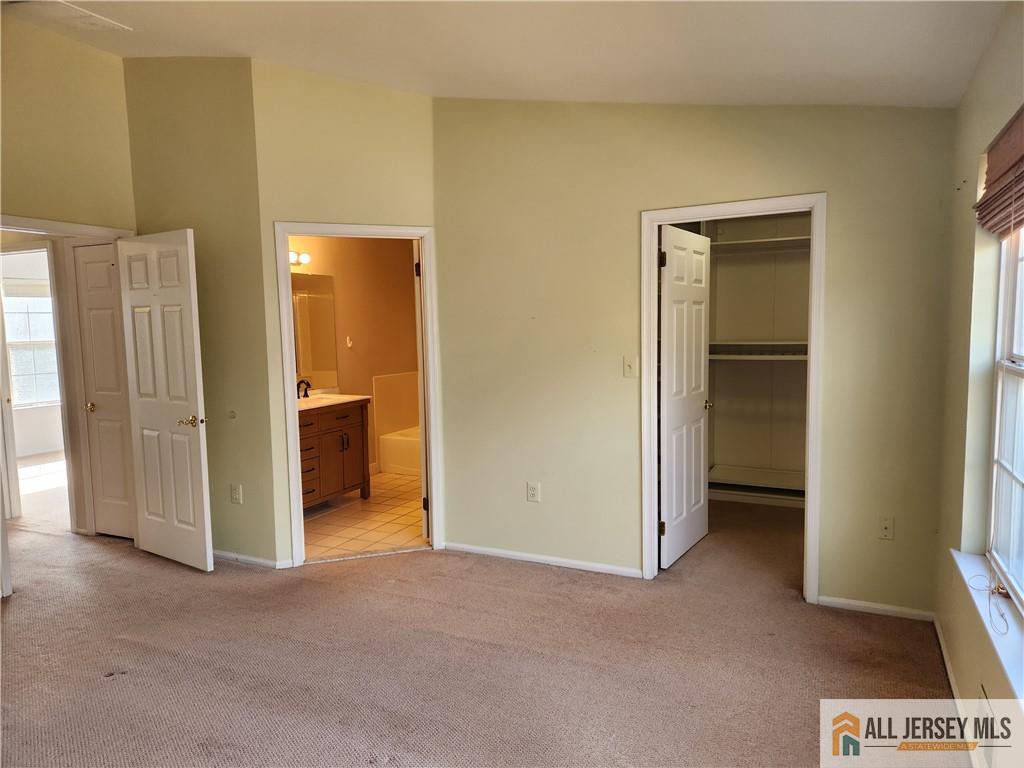 Unfurnished bedroom with carpet, an open closet, and an adjoining bathroom.