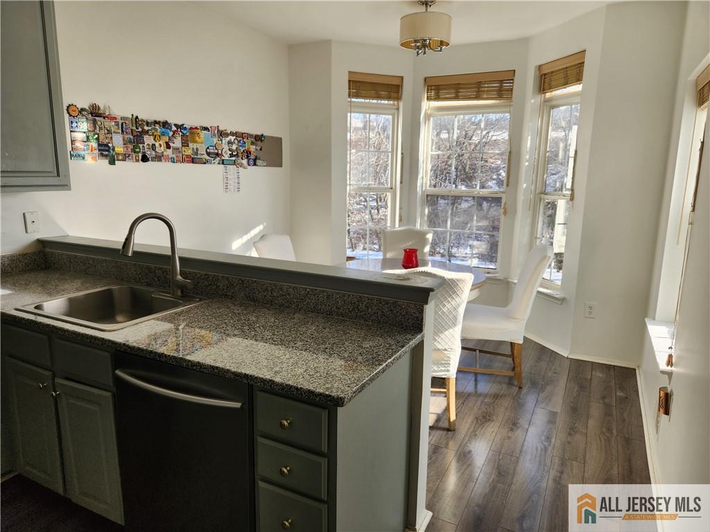 Kitchen and dining nook with granite counters, gray cabinets, and a table beside tall bay windows.
