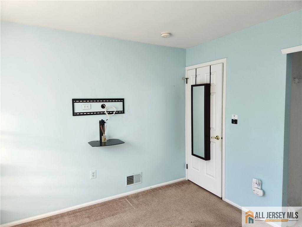 Mostly empty room with pale blue walls, beige carpet, and a mirrored white door.
