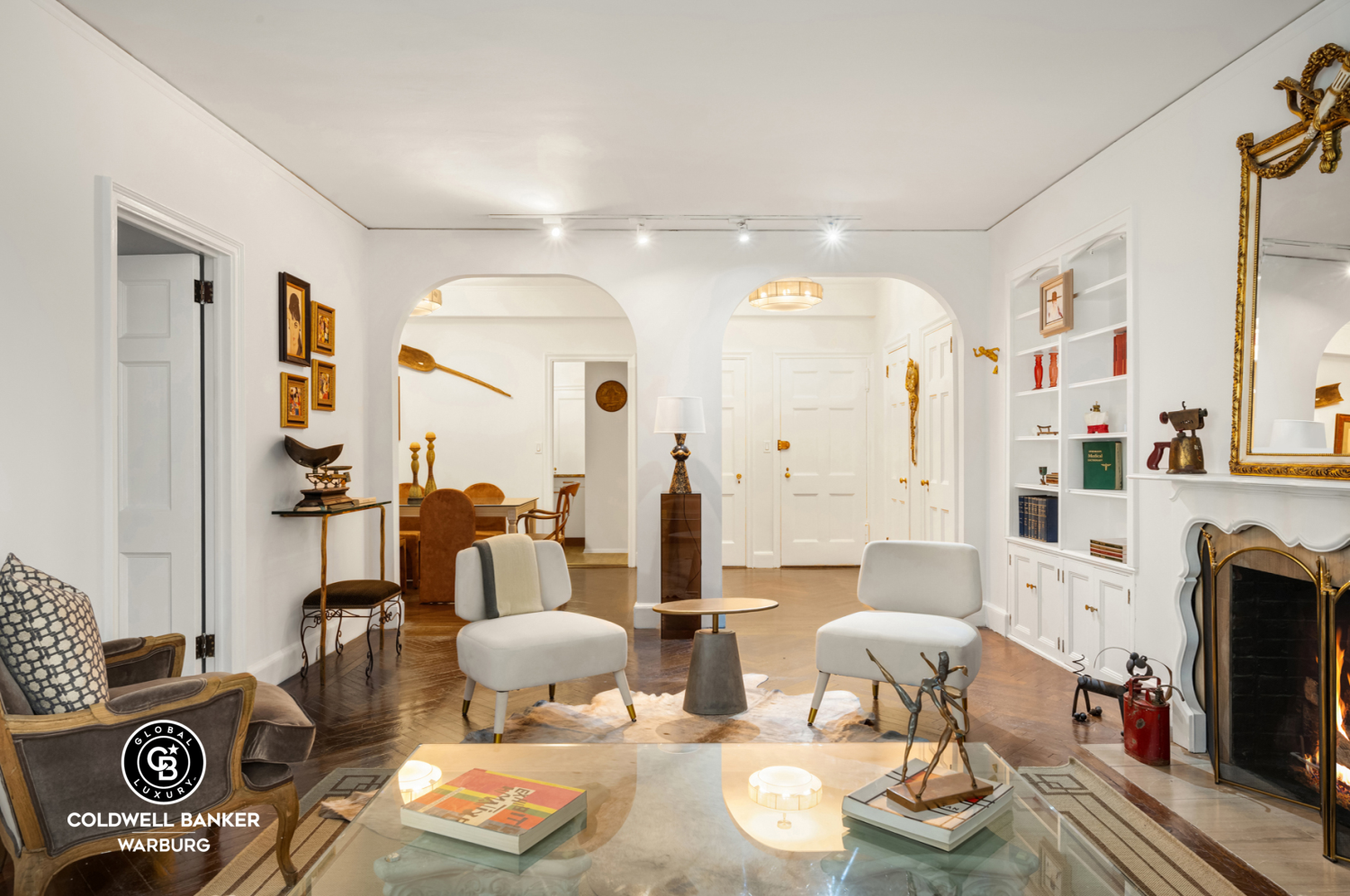 Furnished living room with arched openings, built-in shelving, and an ornate fireplace.