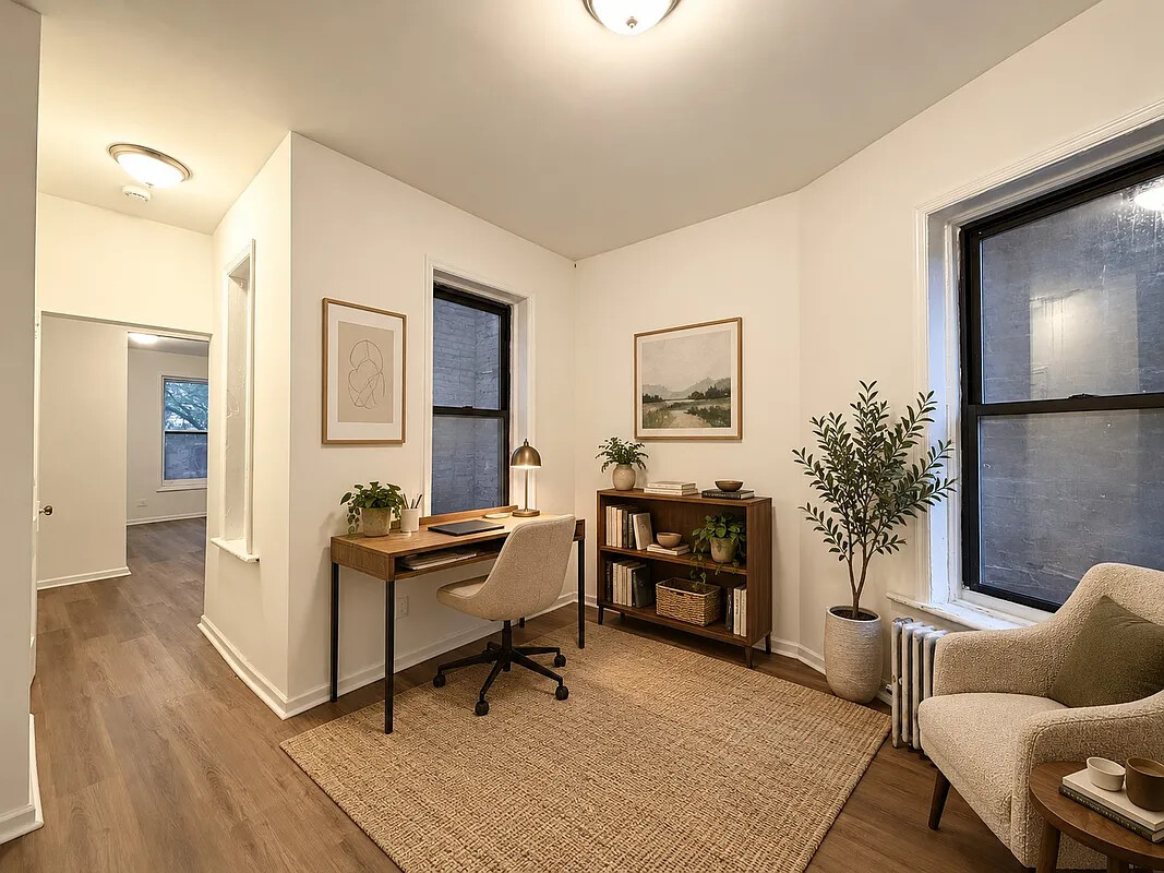 Furnished home office with a wood desk, bookcase, potted plants, and large windows.