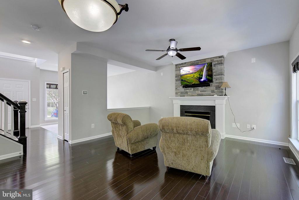 Living room with a stone-surround fireplace, two armchairs, and dark hardwood floors.