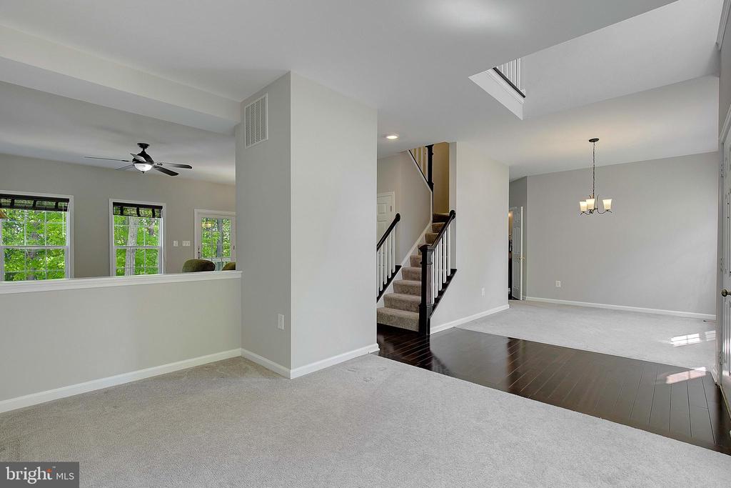 Open, vacant living area with carpet, dark hardwood flooring, and a staircase.