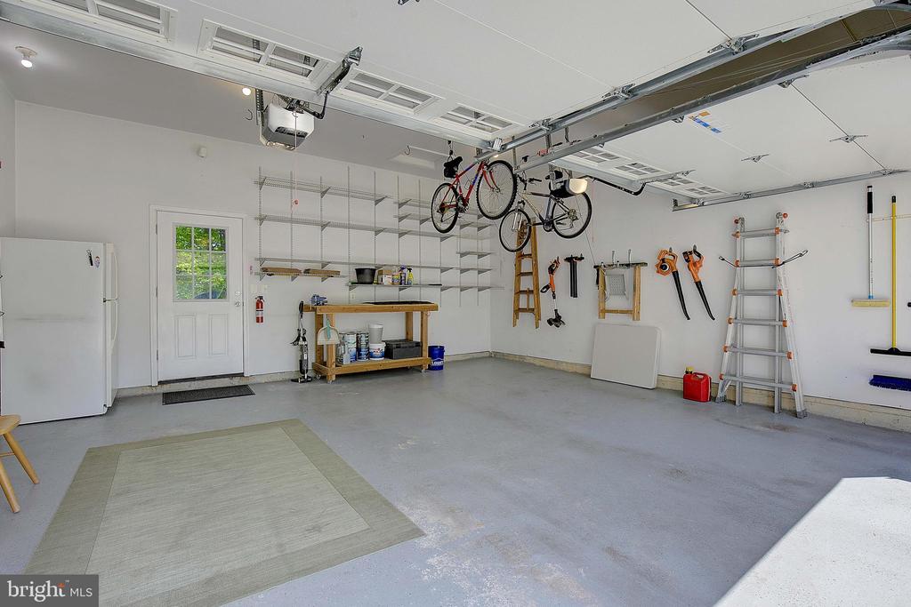 Garage with wall-mounted storage, a workbench, and bicycles suspended from the ceiling.
