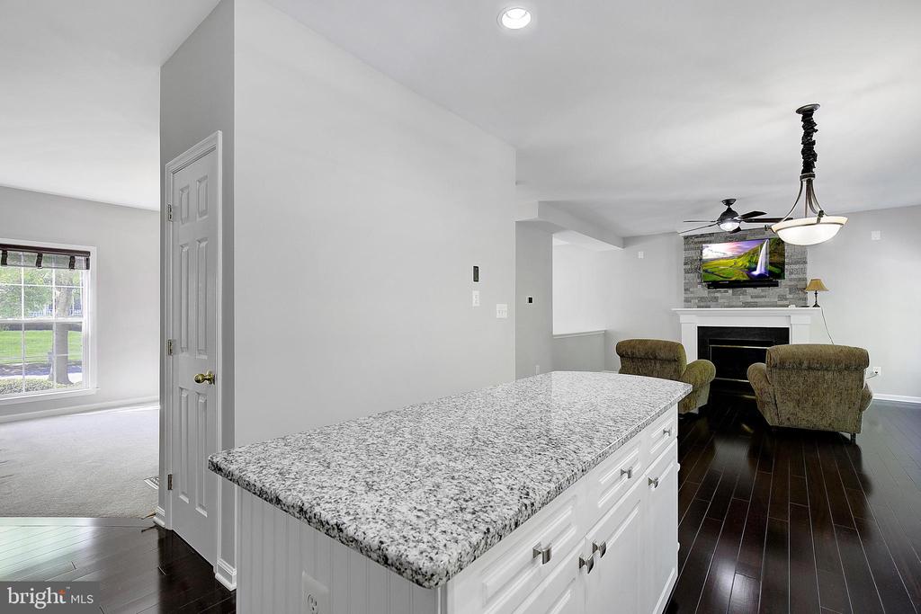 Open-plan kitchen with a granite island, dark hardwood floors, and a living room fireplace.