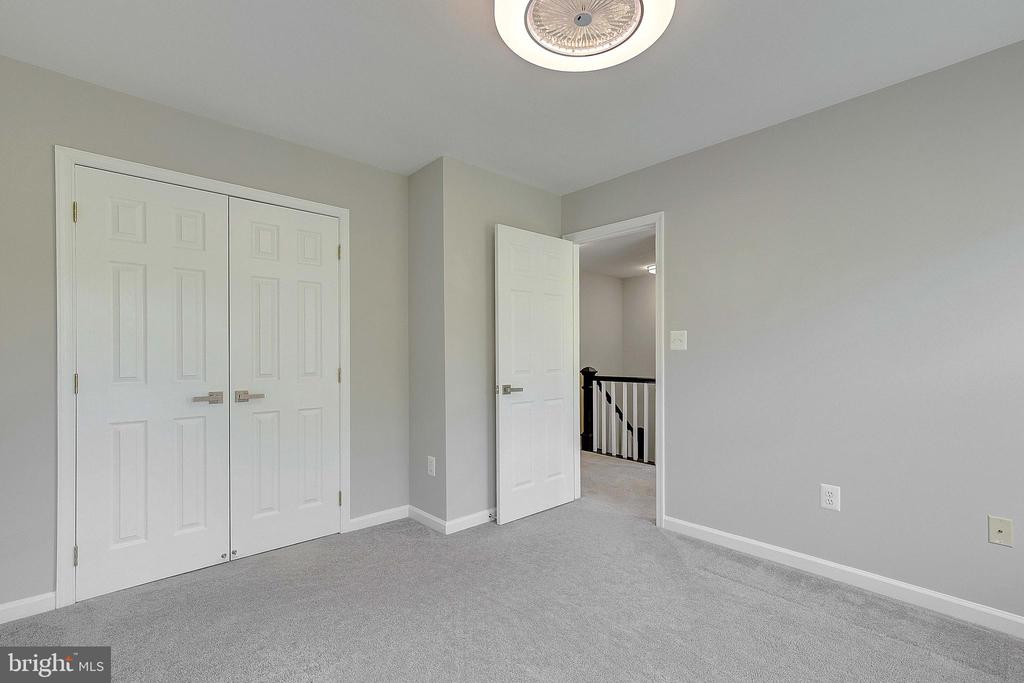 Empty carpeted bedroom with double closet doors and an open doorway to the hall.