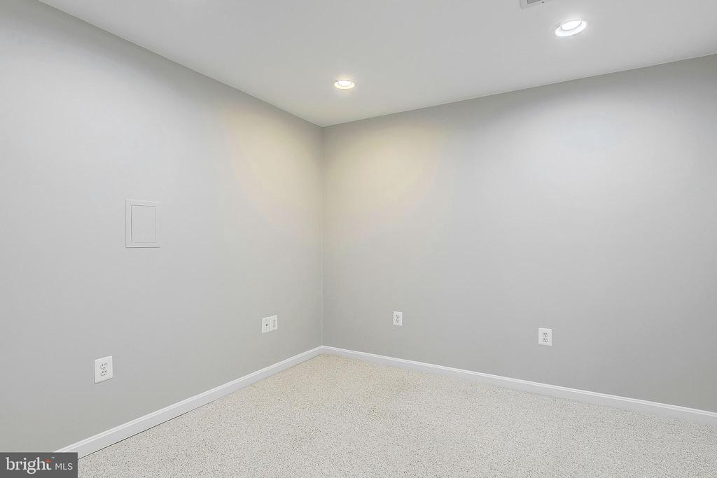 Empty carpeted room with gray walls and two recessed ceiling lights.