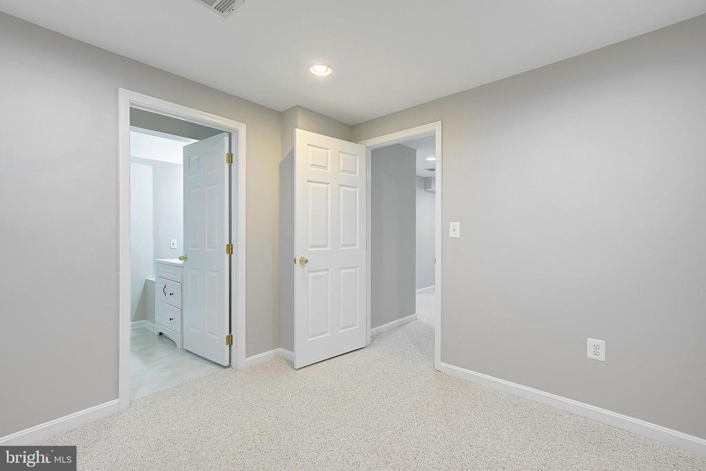 Carpeted room with two open doorways and a bathroom vanity visible beyond one.