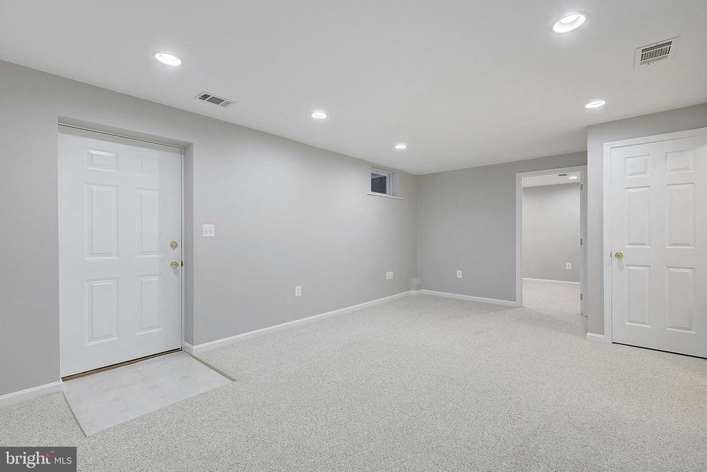 Unfurnished basement room with gray walls, pale carpeting, recessed lights, and two white doors.