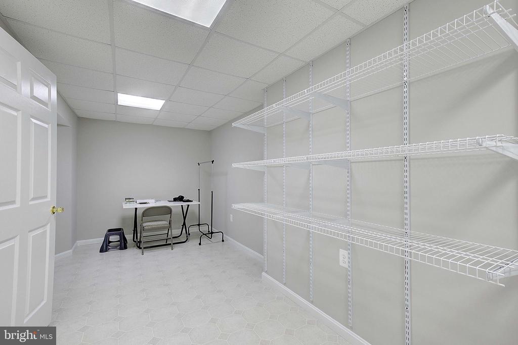 Storage room with empty white wire shelving, pale hexagonal tile, and a folding table.