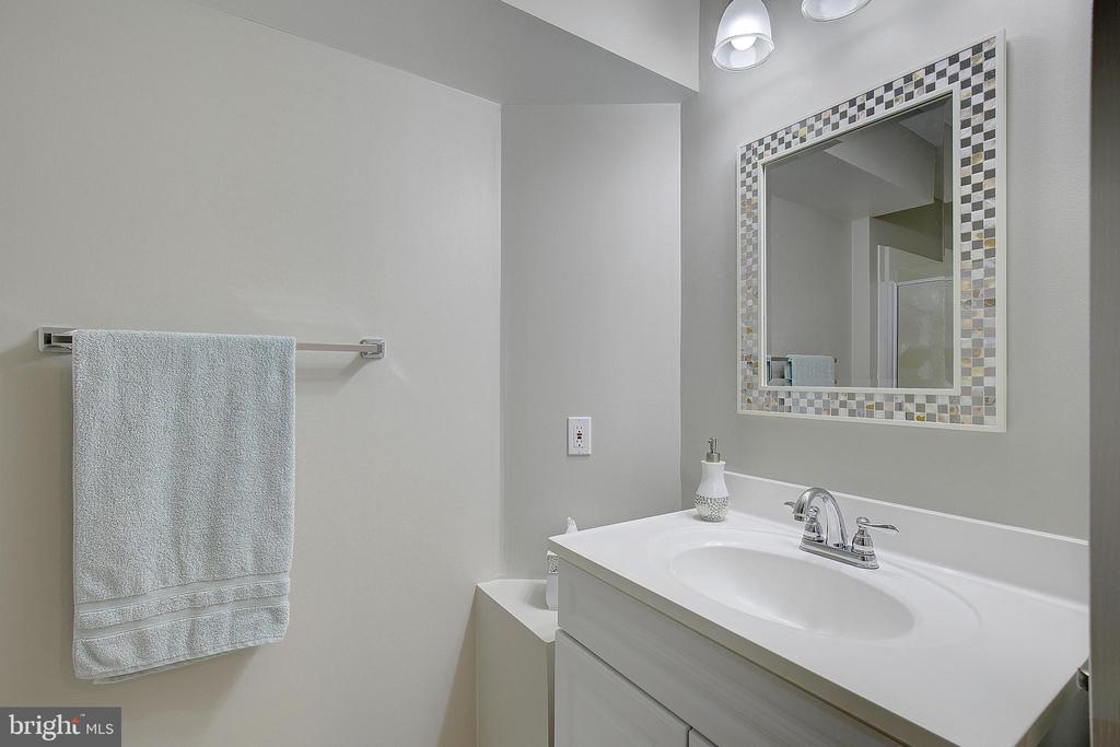 Bathroom vanity with a white sink, chrome faucet, mosaic-framed mirror, and towel bar.