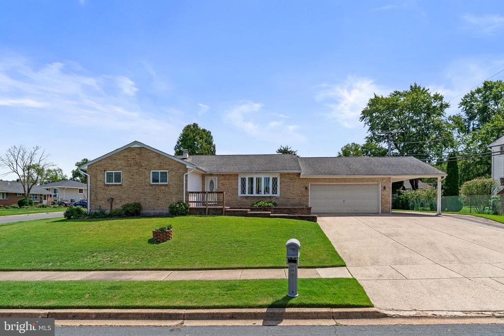 Single-story brick ranch home with an attached garage, wide driveway, and green front lawn.